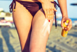 Daylight view to woman applying sunscreen on legs