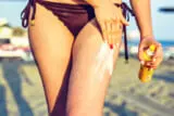Daylight view to woman applying sunscreen on legs