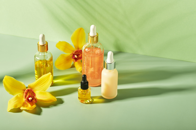 Cosmetic care products in glass bottles with orchid flowers - serums, cream, gel, oils. Concept for face and body care, wellness and spa, tropical relaxation.