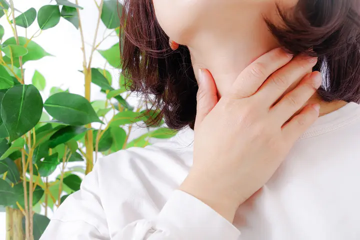 喉をおさえる女性